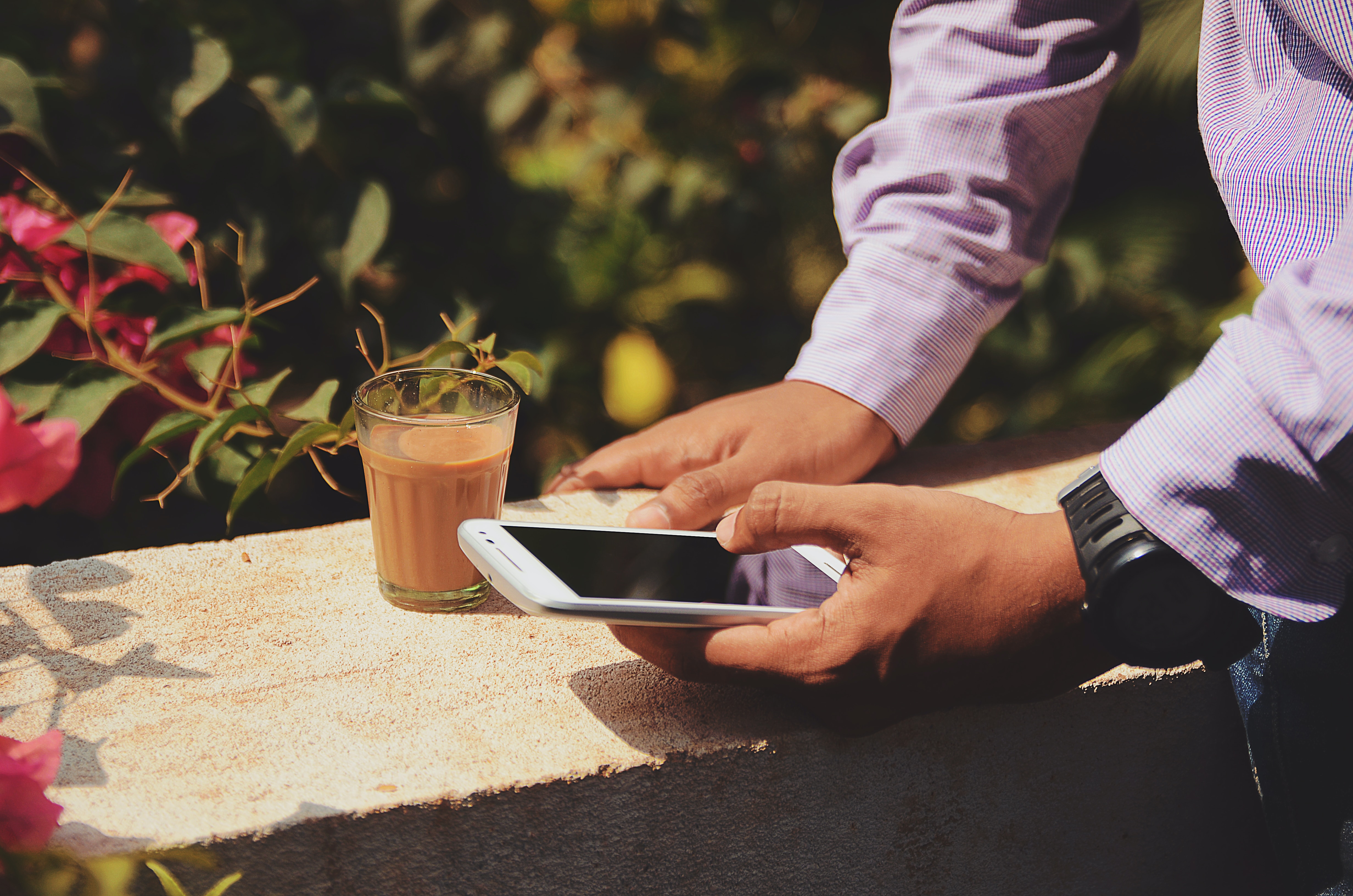 man using smartphone beside drinking glass